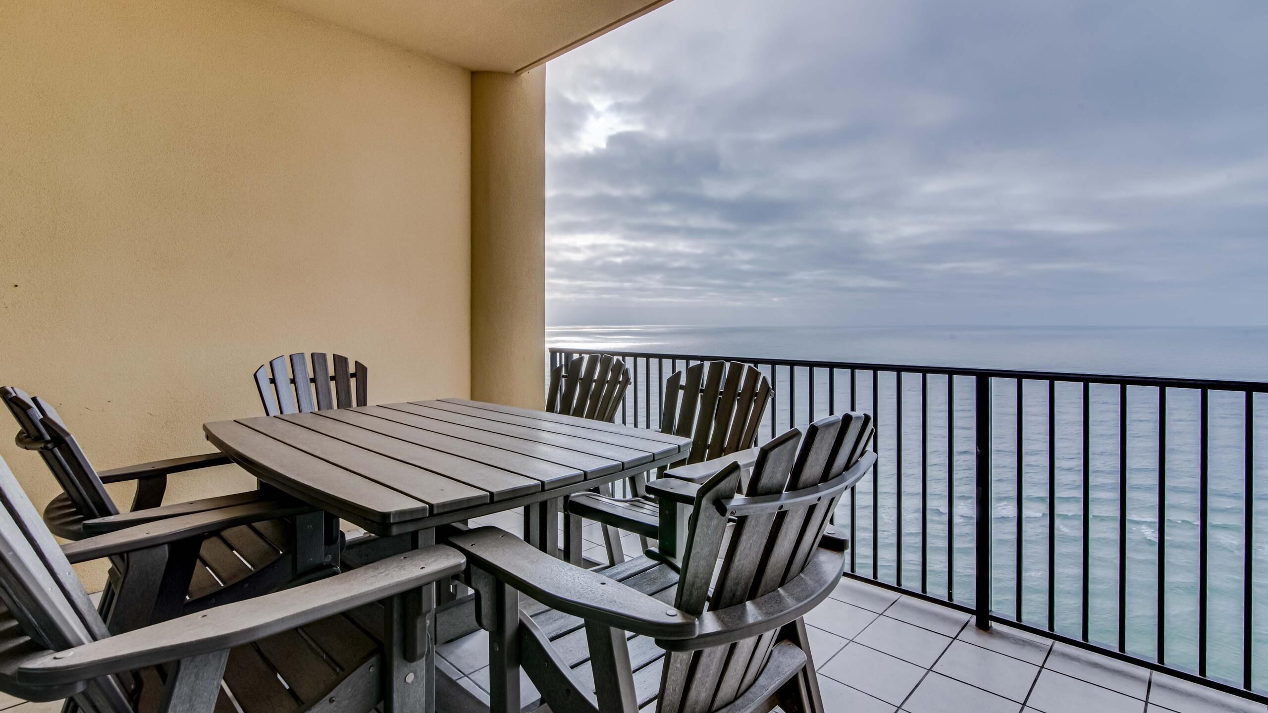 Ein Balkon mit Tisch und Stühlen, mit Blick auf ein Gewässer.