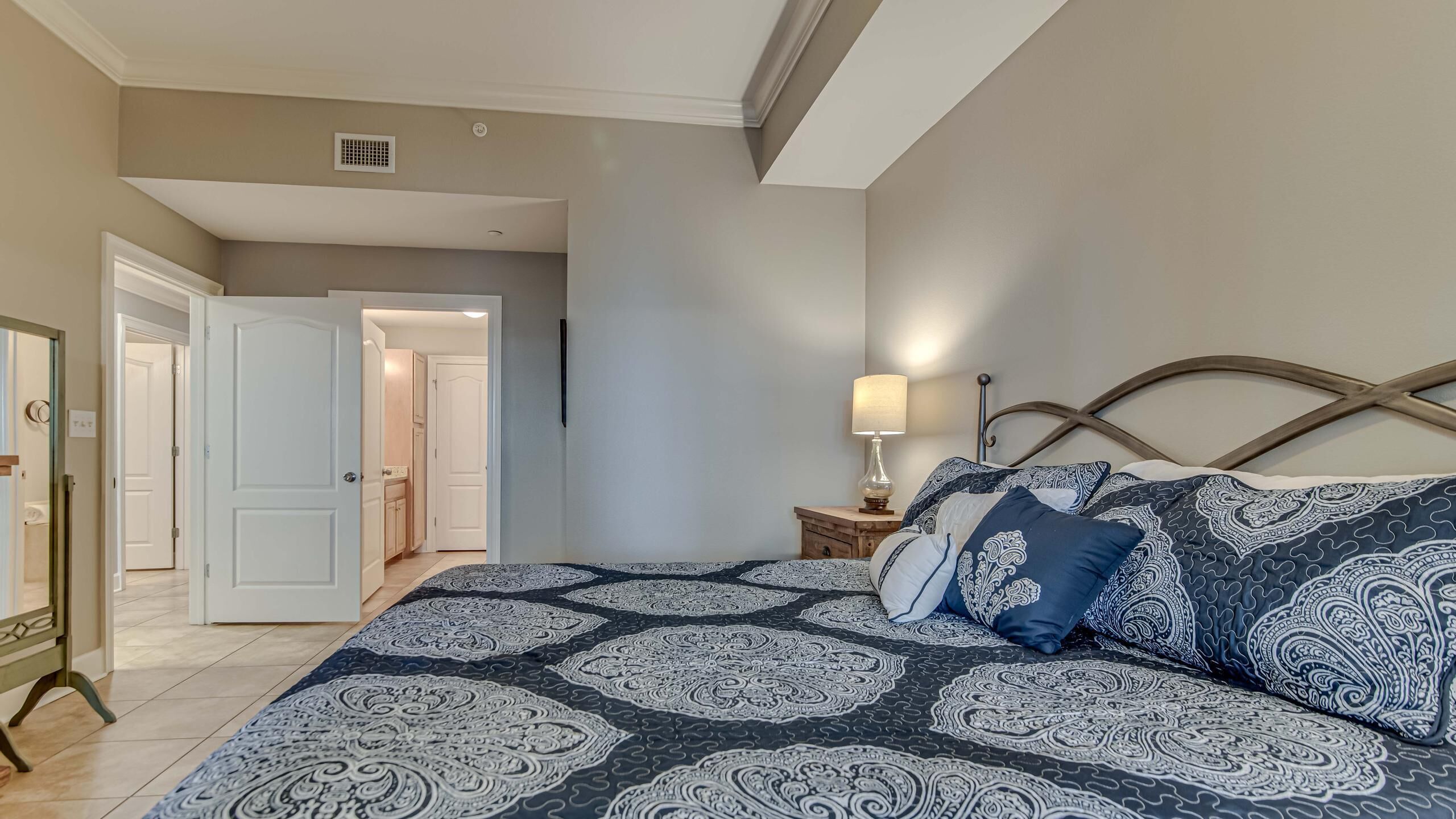 A bedroom with a large bed, a bedside table with a lamp, and a wardrobe.