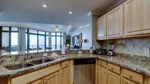 A modern kitchen with granite countertops, wooden cabinets, and a built-in dishwasher.