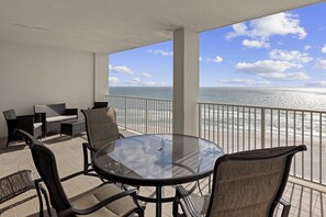 A balcony with a glass table and chairs, overlooking the ocean. - Windward Pointe by Southern Vacation Rentals (Orange Beach)