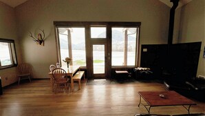 Un salon spacieux doté d’un plancher en bois, d’une table à manger avec des chaises, d’un canapé et d’une cheminée.