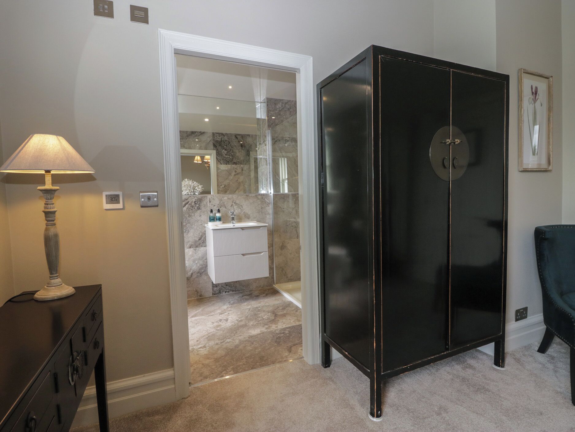 A bathroom with a vanity, a mirror, a cabinet, and a shower area.