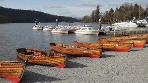A lakeside dock with several wooden boats and a few motorboats. - The Boundary (Windermere)