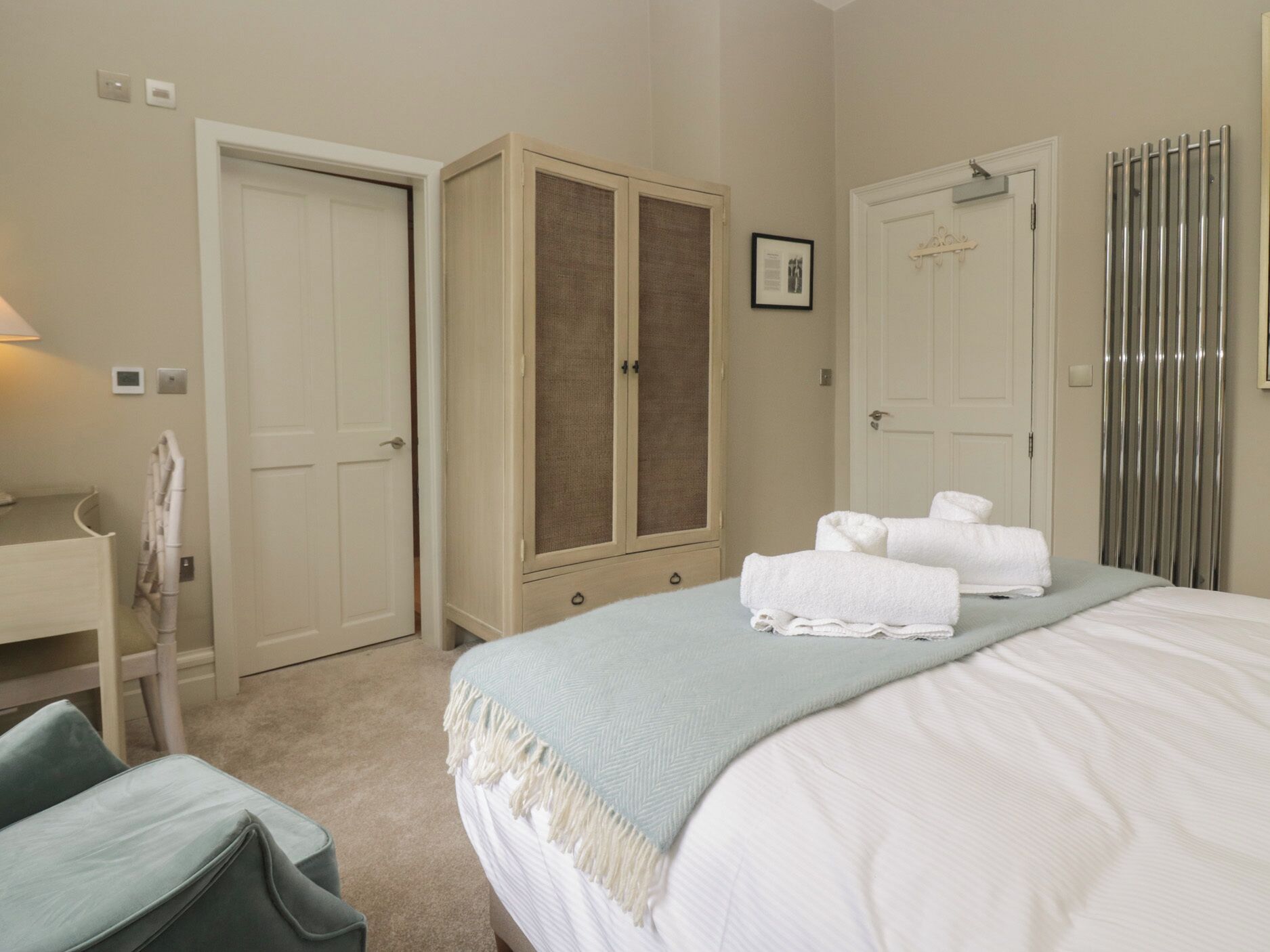 A bedroom with a bed, a wardrobe, a bathroom with a towel rack, and a shower curtain.