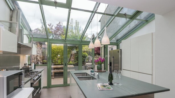 A modern kitchen with a large island, stainless steel appliances, and a glass-enclosed patio area. - The Boundary (Windermere)