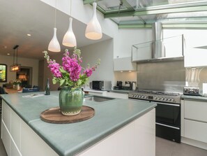 A modern kitchen with a central island, stainless steel appliances, and pendant lighting.