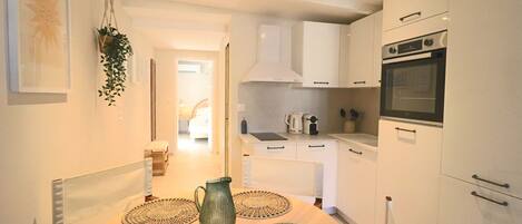 A modern kitchen with white cabinets, a built-in oven, and a dining area with a table set for two.