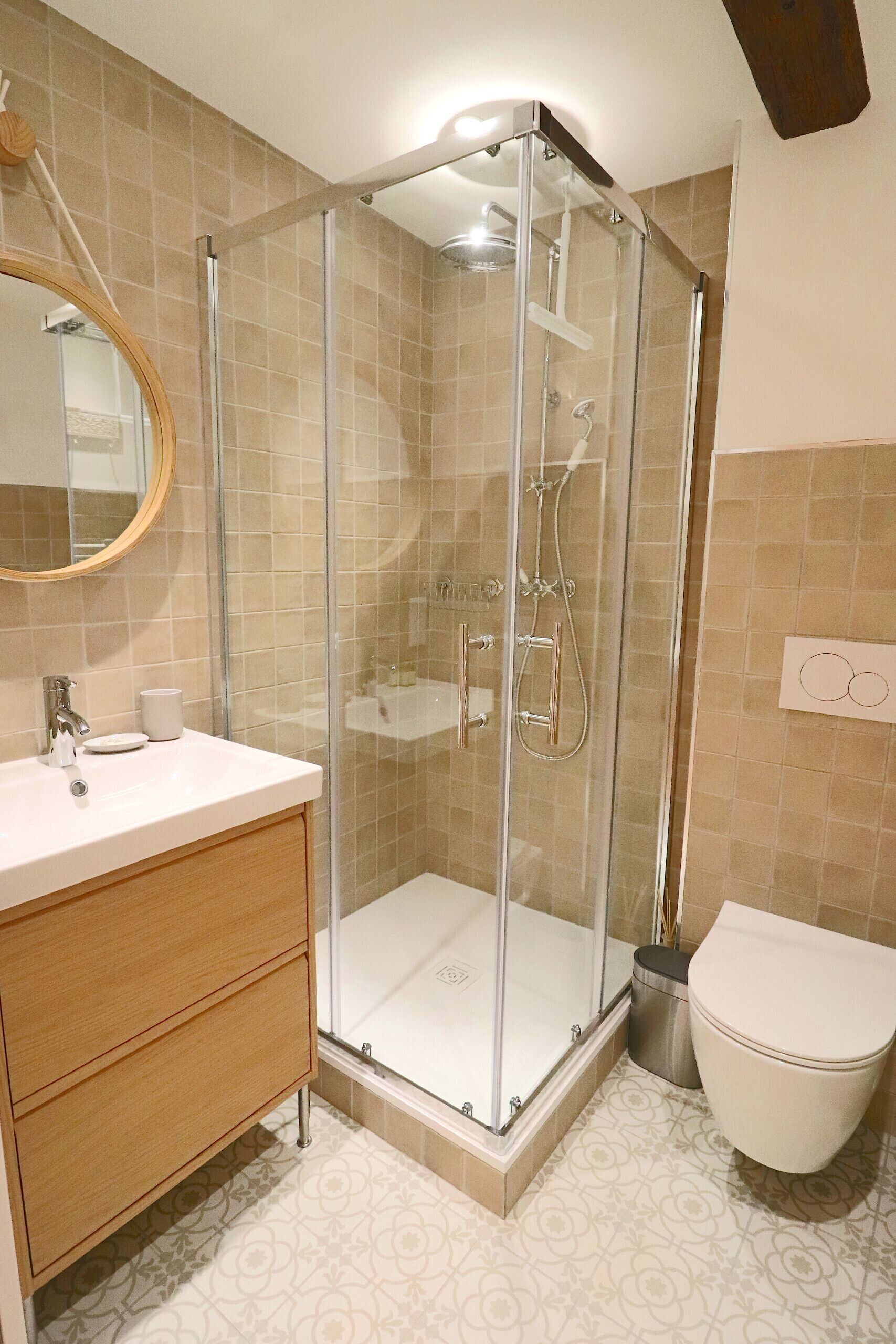 A bathroom with a glass-enclosed shower, a wooden vanity, and a toilet.