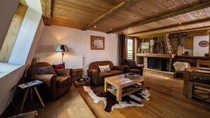 A cozy living room with wooden flooring, leather sofas, a coffee table, and a fireplace. - La Cachette - Mountain style and spacious 2-Bed apartment central Chamonix (Chamonix-Mont-Blanc)