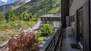 A balcony with a view of a mountain, a parking lot, and a building with multiple floors. - La Cachette - Mountain style and spacious 2-Bed apartment central Chamonix (Chamonix-Mont-Blanc)