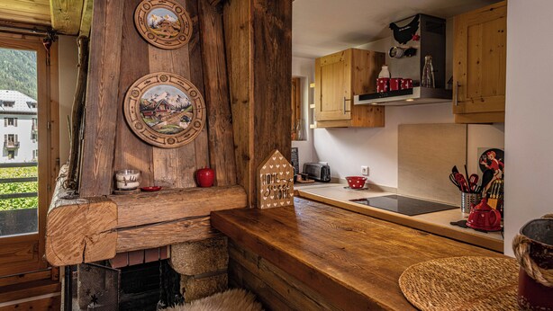A rustic kitchen with wooden beams, a fireplace, and a view of a mountain. - La Cachette - Mountain style and spacious 2-Bed apartment central Chamonix (Chamonix-Mont-Blanc)