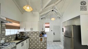Una cucina con mobili bianchi, piano cottura a gas, frigorifero e piastrelle decorative a parete.