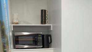 A compact kitchen with a microwave, coffee maker, and a small refrigerator. - Excellent place (Magna)