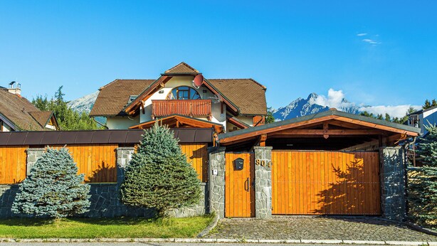 Un chalet doté d’une façade en pierre, de balcons en bois et surplombant un paysage montagneux.