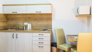 Une cuisine compacte avec un plan de travail en bois, un évier, une bouilloire et un petit coin repas comprenant une table et des chaises.