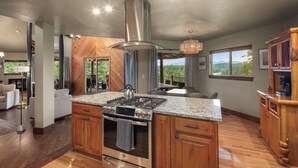 Una cocina con una isla grande, electrodomésticos de acero inoxidable, armarios de madera y vistas al exterior.