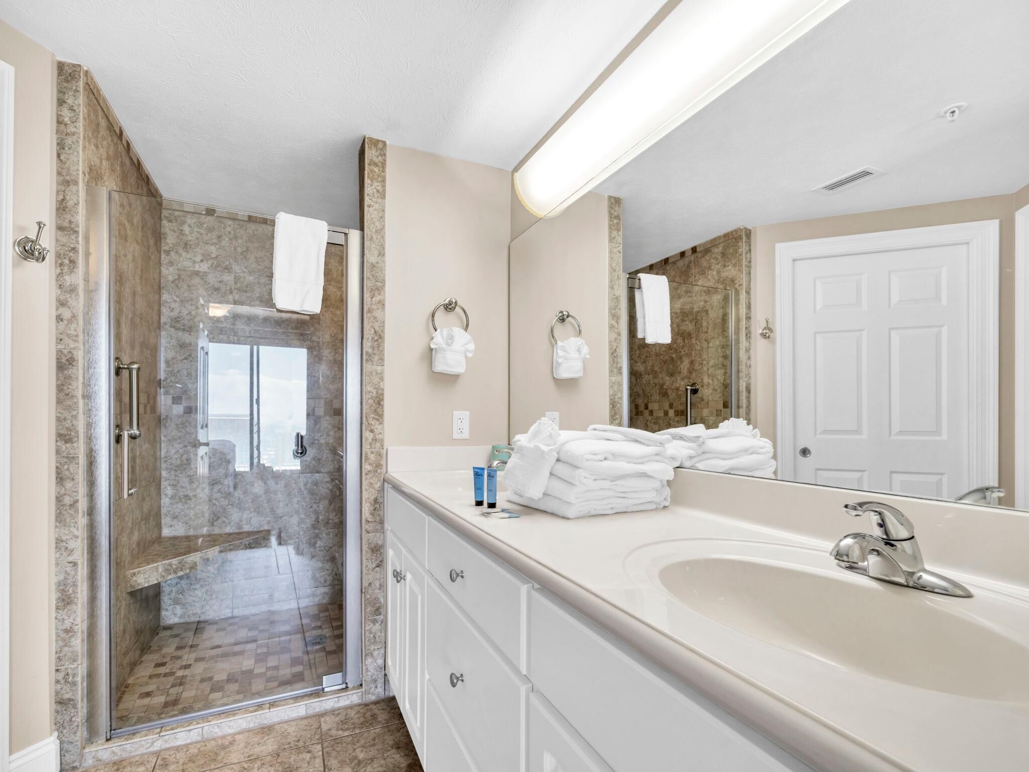 Une salle de bain moderne avec une douche à parois de verre, un grand meuble-lavabo et un miroir.