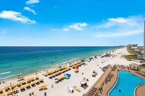 A beach resort with a pool, sun loungers, and umbrellas. - Treasure Island 605 (Panama City Beach)