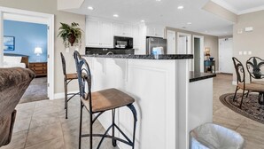 A modern kitchen with white cabinetry, a granite countertop, and recessed ceiling lights.
