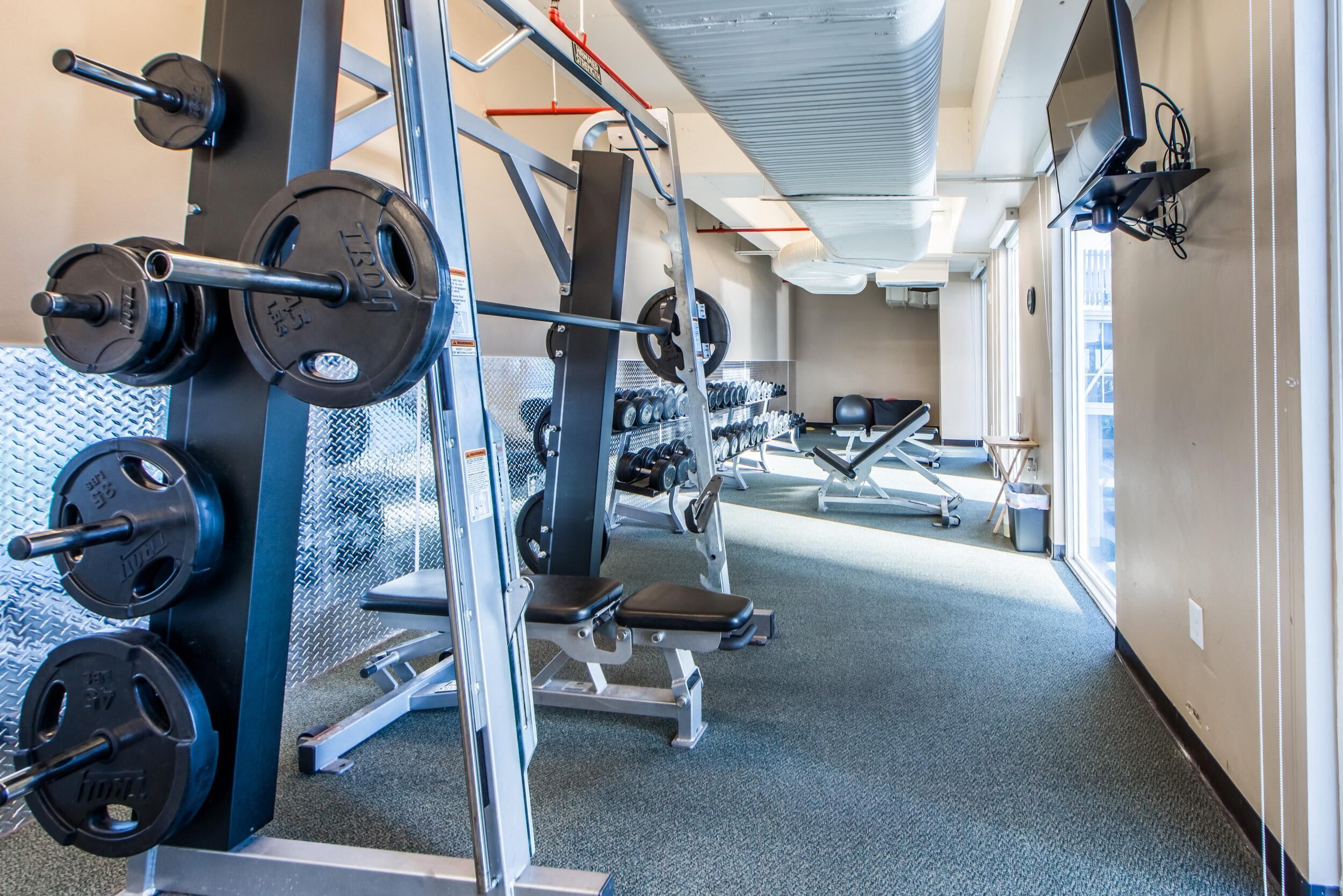 A gym with weightlifting equipment, treadmills, and exercise machines.