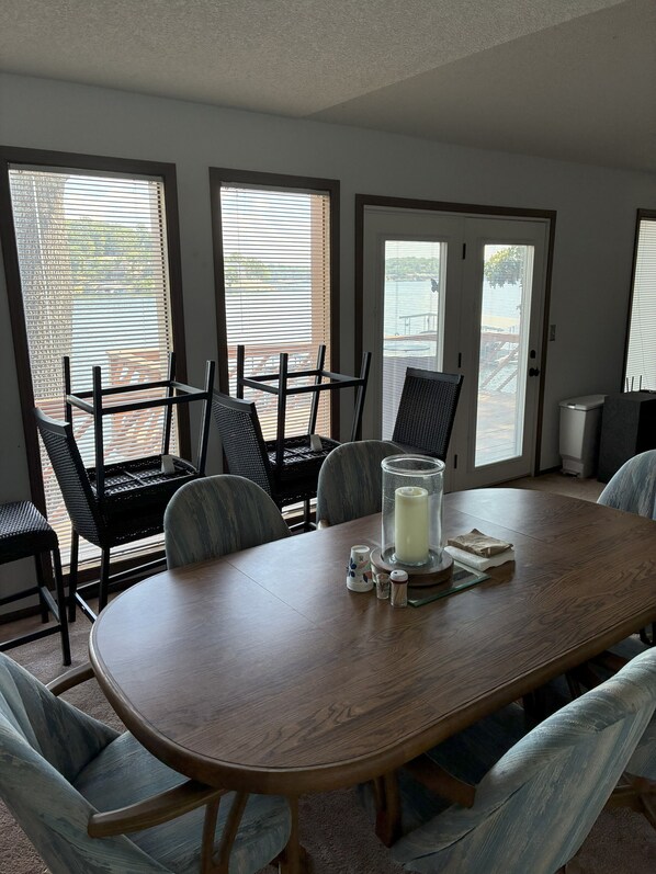 Un comedor con una mesa de madera, sillas negras y un candelabro de vidrio.