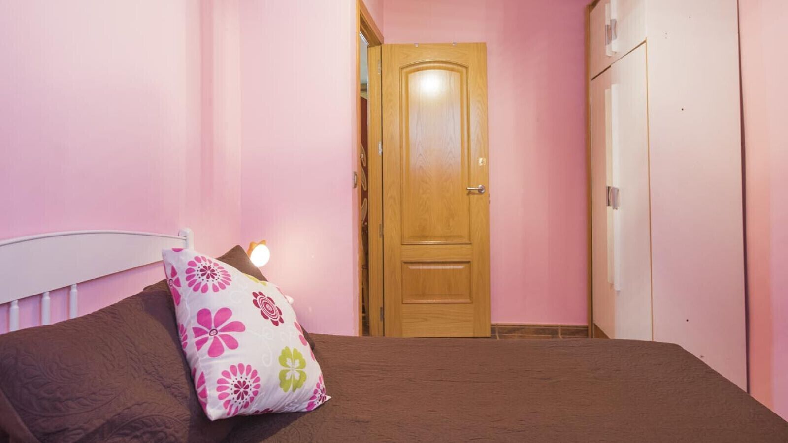 A bedroom with a bed, a wooden door, and a wardrobe.