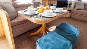 Ein modernes Wohnzimmer mit Essbereich, ausgestattet mit Sofas, einem Couchtisch und einem Fernseher.