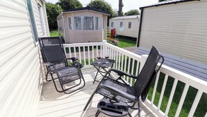Eine Terrasse mit zwei schwarzen Stühlen und einem kleinen Tisch, umgeben von weißen Geländern.