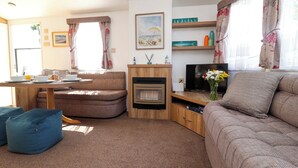 Ein gemütliches Wohnzimmer mit einer Couch, einem Esstisch mit Frühstücksangebot, einem Fernseher und einem Kamin.