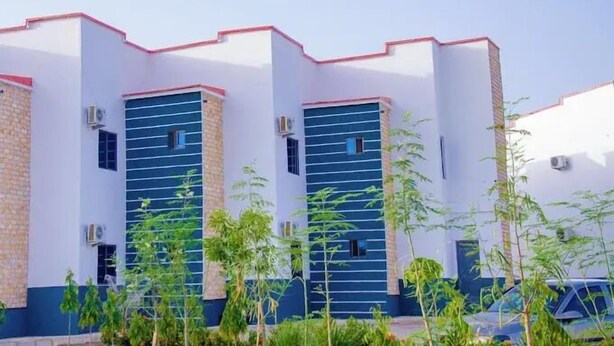 Un edificio con fachada blanca y detalles en rojo, con ventanas grandes y unidades de aire acondicionado.