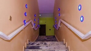 Una escalera de mármol con barandillas blancas y luces azules en las paredes.