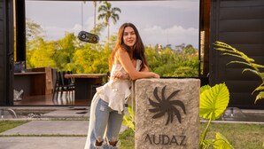 A woman leaning on a stone pillar with the name 'AUDAZ' engraved on it, set against a backdrop of lush greenery and a modern building. - Casa Audaz: Private Pool, Jacuzzi & Daily Cleaning in a Peaceful Escape (Circasia)