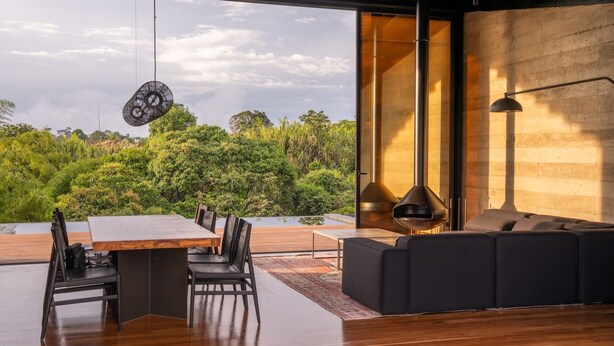A modern interior with a dining area, a sofa, and a large window overlooking a lush garden. - Casa Audaz: Private Pool, Jacuzzi & Daily Cleaning in a Peaceful Escape (Circasia)