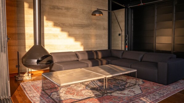 A modern living room with a sectional sofa, a coffee table, and a large fireplace.