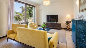 A modern living room with a sofa, TV, and decorative items. - Apartment Righini with Pool (Torri del Benaco)