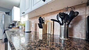 A kitchen with granite countertops, a coffee maker, a paper towel holder, and a knife block.