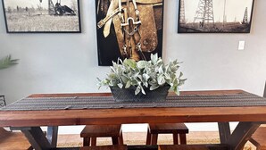 A wooden dining table with benches, a potted plant, and two framed pictures on the wall.