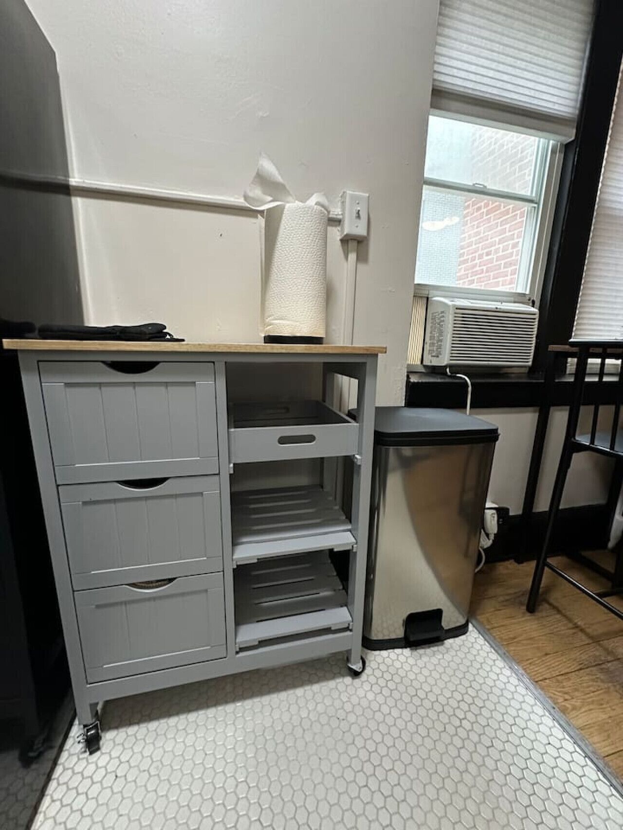 Una kitchenette con un armario gris, una encimera y un pequeño cubo de basura.