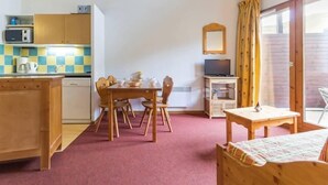 Una habitación compacta con kitchenette, zona de comedor, televisor y cama.