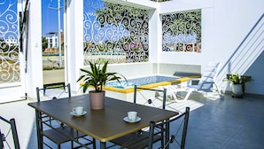Un patio al aire libre con piscina, una mesa y sillas, y ornamentación de hierro.