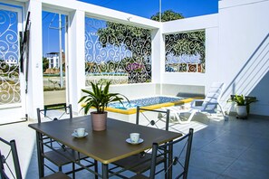 Eine Terrasss mit Pool, Tisch und Stühlen sowie dekorativem Eisenwerk.