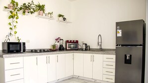 A modern kitchen with white cabinets, a stainless steel refrigerator, a microwave, an oven, and a sink. - Sol y Relax Family Home in Huacachina, Ica (Ica)