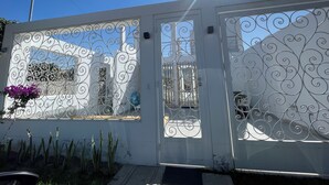 A white building with decorative metal gates and a clear blue sky. - Sol y Relax Family Home in Huacachina, Ica (Ica)