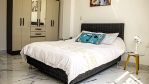 A bedroom with a bed, a wardrobe, a nightstand, and a painting on the wall. - Sol y Relax Family Home in Huacachina, Ica (Ica)