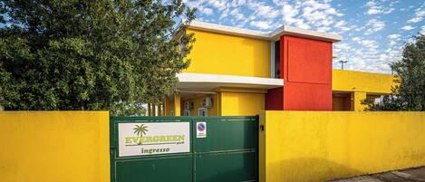 Un edificio con una puerta verde que lleva la inscripción 'EVERGREEN park' y una fachada amarilla y roja.