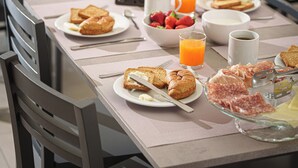 Una mesa de desayuno lista con tostadas, pasteles y un bol de fruta.