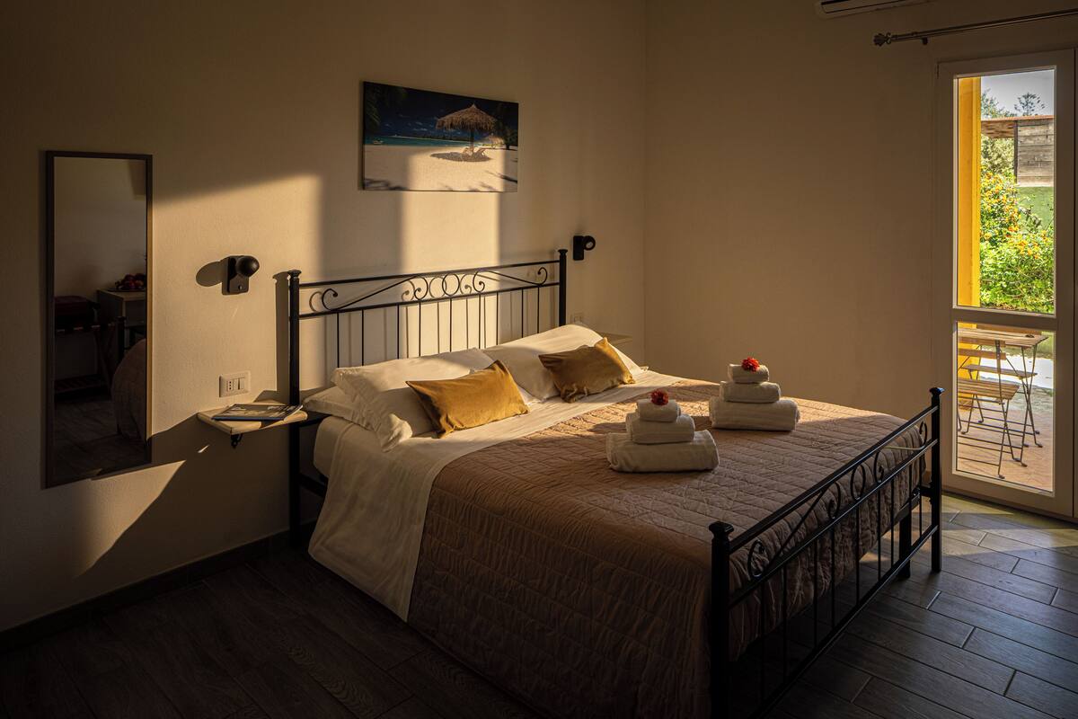 Una cama bien hecha con cabecera, una mesita de noche y un cuadro en la pared.