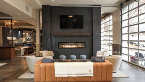 A modern living room with a fireplace, comfortable seating, and large windows.