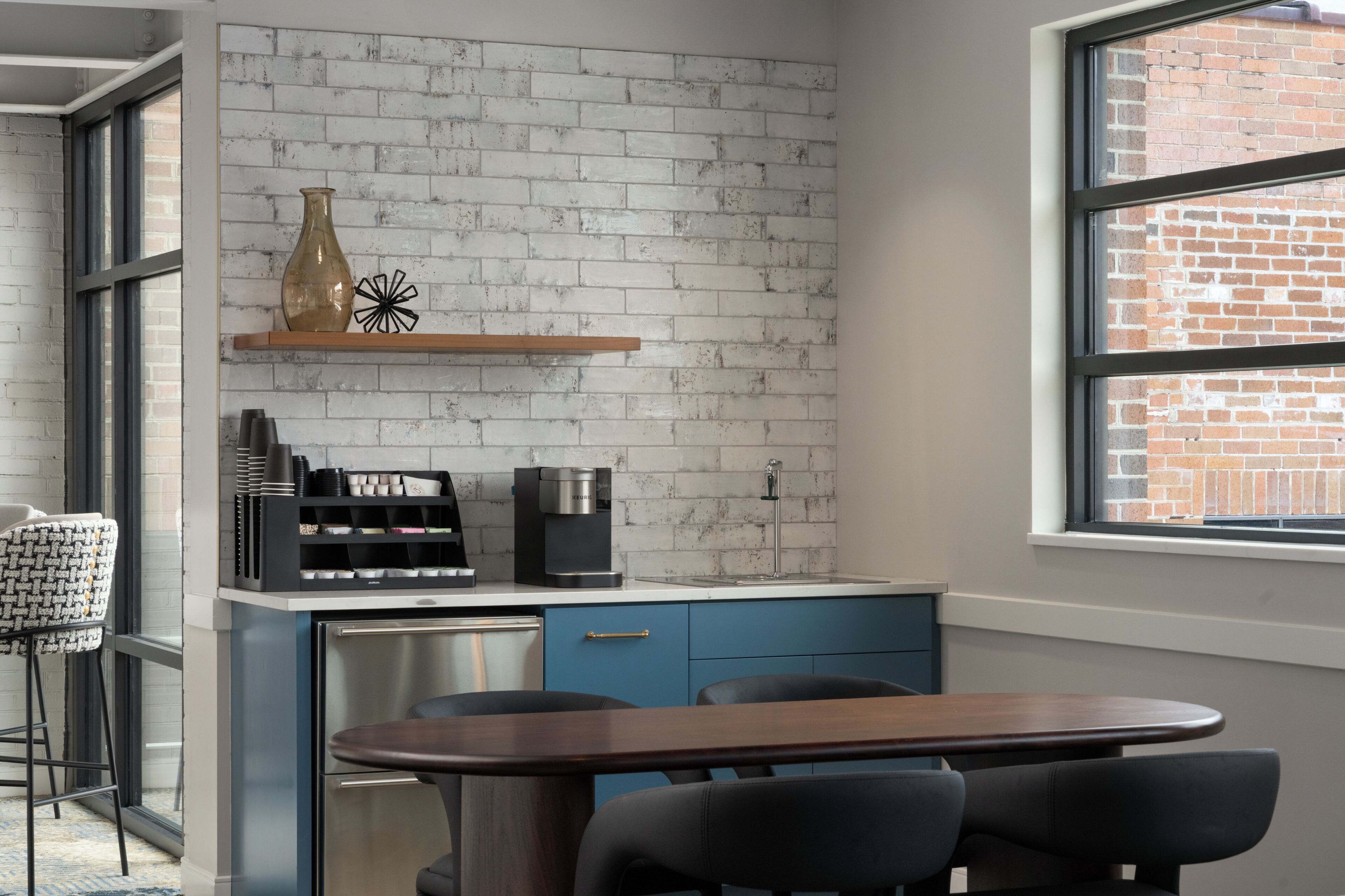 Una cocina moderna con salpicadero de ladrillo, una cafetera y un comedor con mesa y sillas.