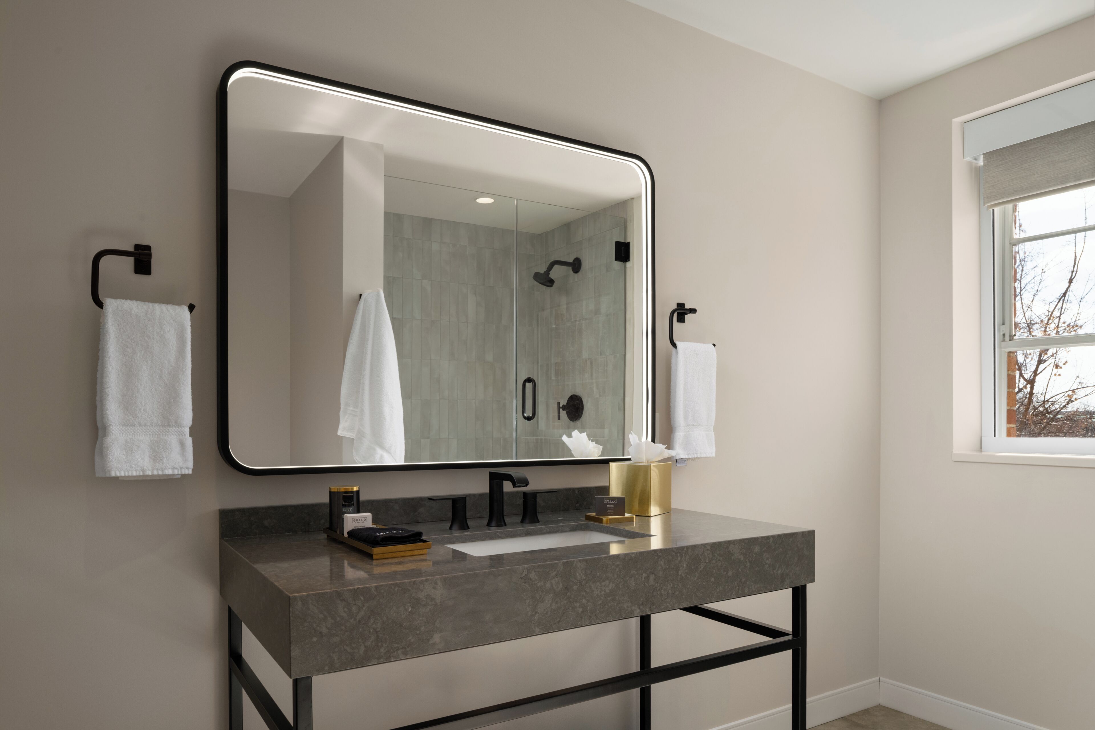 Une salle de bain moderne avec un grand miroir, un lavabo et une douche.